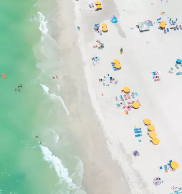 Aerial view of yellow beach cabanas and emerald-green waters of Treasure Island.