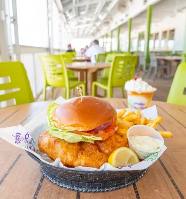 a fried grouper sandwich on a brioche bun with tartar sauce and a lemon