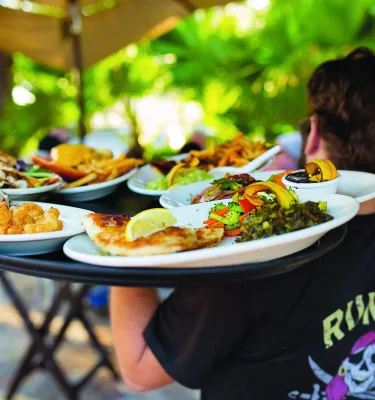 Waiter carries tray of seafood and other dishes
