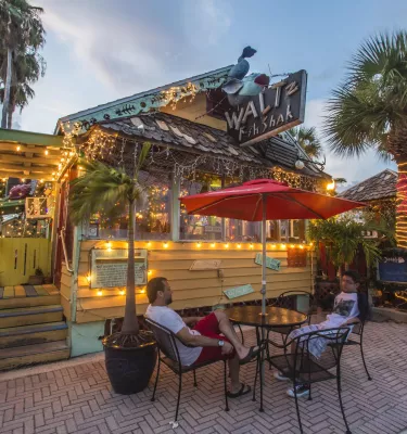 Exterior of a small, funky fish shack with one table out front