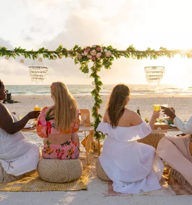 Four women enjoy an elaborate picnic on the beach