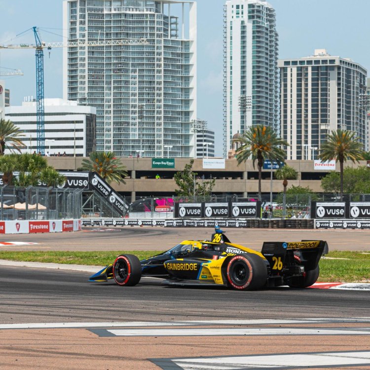 An Indy Car races along the track of the Firestone Grand Prix with the Saint Pete skyline in the background.