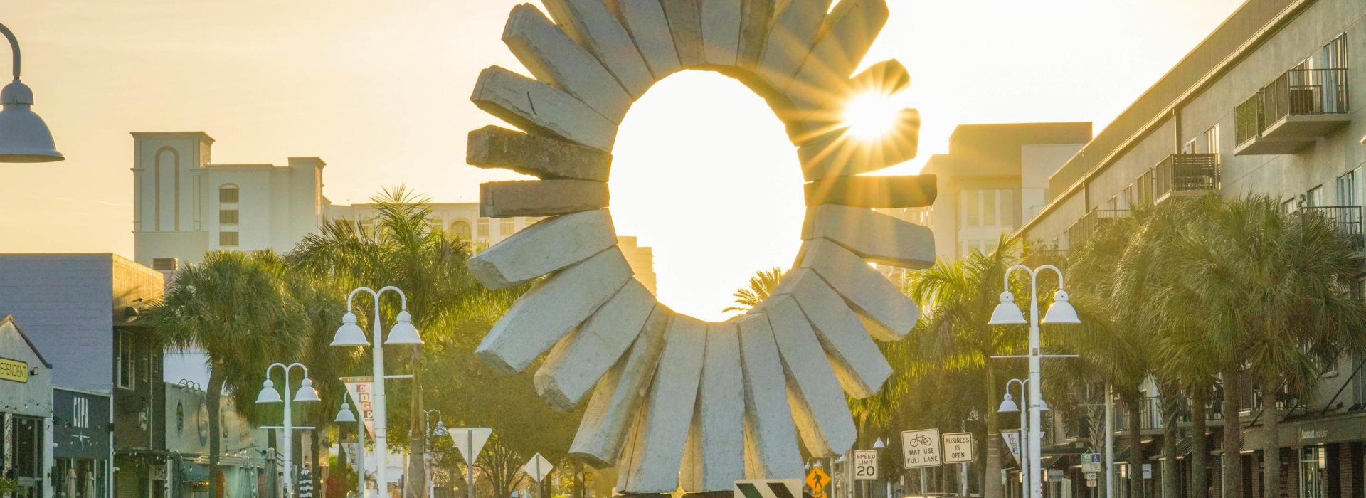 The sun rises behind a stone sun sculpture in Saint Pete's Edge District.