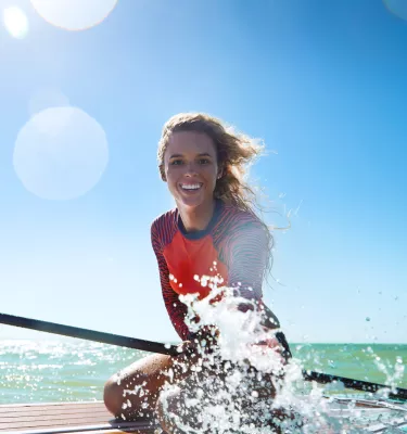 A young woman on a paddleboard splashes water in Anclote Key.