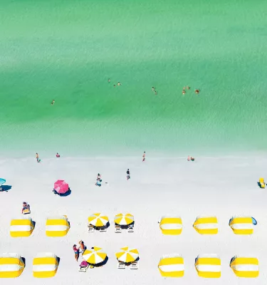 Aerial view of yellow cabanas, white sand and emerald-green water of Clearwater Beach.