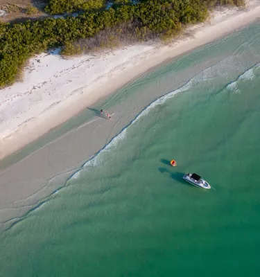 Aerial view of a boat anchored off the beach at Shell Key Preserve; dunes border the beach and the Gulf water is emerald green