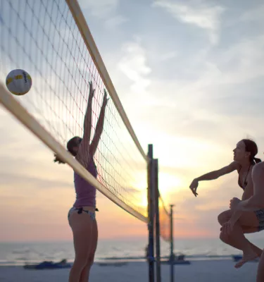 A group of woman play volleyball in St. Pete Beach as the sun sets.