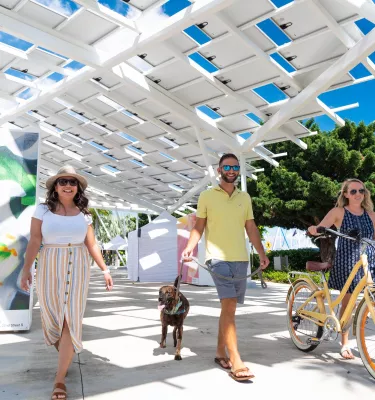 Three people and a dog stroll down the St. Pete Pier Marketplace