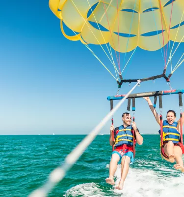A couple taking flight in a parasail in Clearwater Beach.
