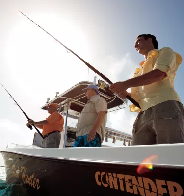 A group of men in a black boat fishing.