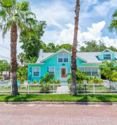 A blue house with palm trees around it seen from the road in Gulfport.