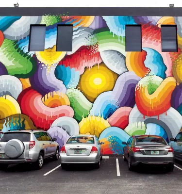 Several cars parked in front of a colorful mural