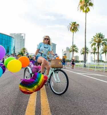 A person with colorful balloons tied to their bicycle riding during Pride parade in St. Pete.