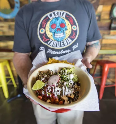 A waiter holds up a taco bowl from Casita Taqueria in downtown St. Pete