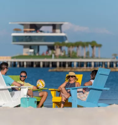 Four friends lounge in Adirondack chairs at spa beach at the new St. Pete Pier