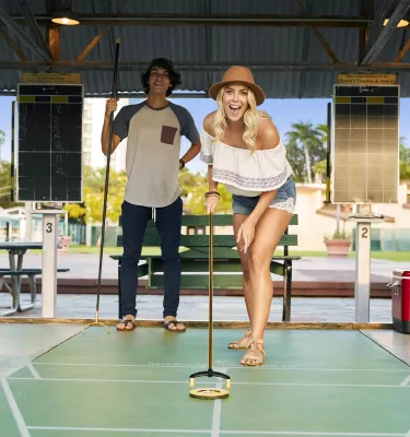 A woman pushes a disc on a shuffleboard at the St. Pete Shuffleboard Club