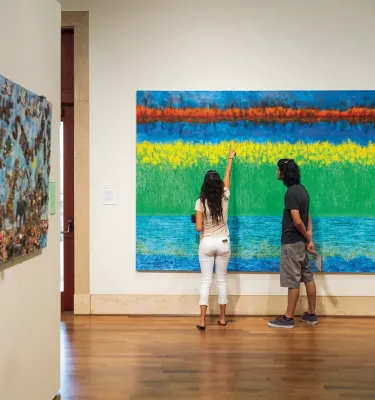 A couple looking closely to a painting at the St. Pete Museum of Fine Arts.