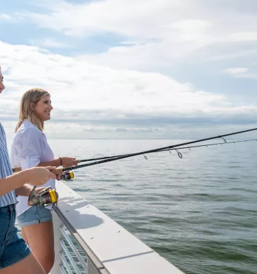 Two caucasian young ladies fishing off of St. Pete Pier.