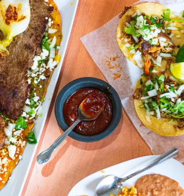 Colorful tacos on a plate next to a skirt steak with a green adobo pepper at El Huarache Veloz mexican restaurant in Pinellas Park