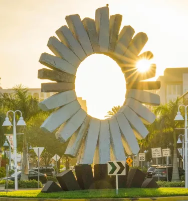 The sun rises behind a stone sun sculpture in Saint Pete's Edge District.