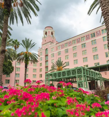 magenta and light pink zinnia flowers and two palm trees accent the large pink historic hotel the Vinoy Renaissance