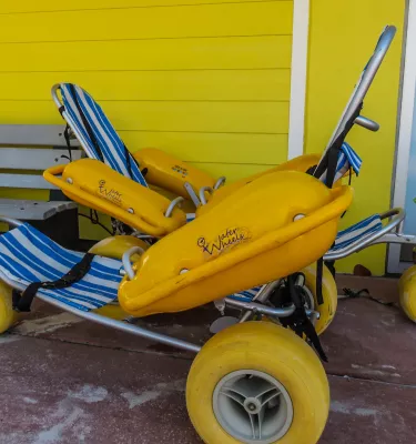 a bright yellow beach wheelchair that is styled like a lounge chair