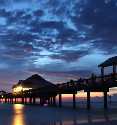 deep blue and purple sunset with clouds over Pier 60 which is illuminated by lights underneath