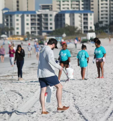 People clean up trash on the beach