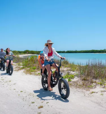 A family on electric bikes bicycle along a waterfront bike path