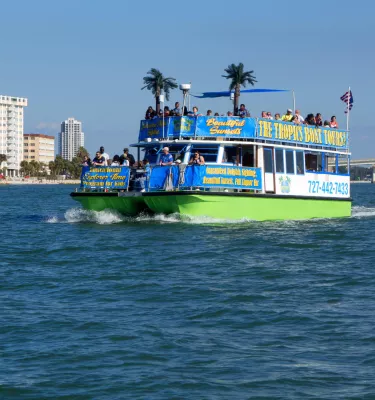 A tropical-themed tour boat cruises through the water during the day.