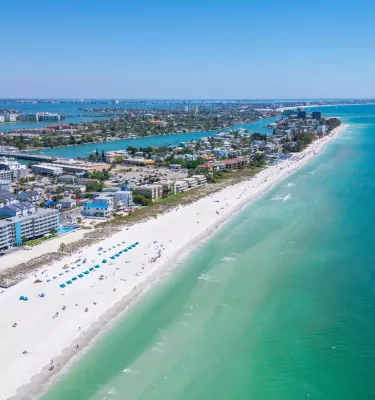An aerial view of the ocean, beach and buildings along the shore