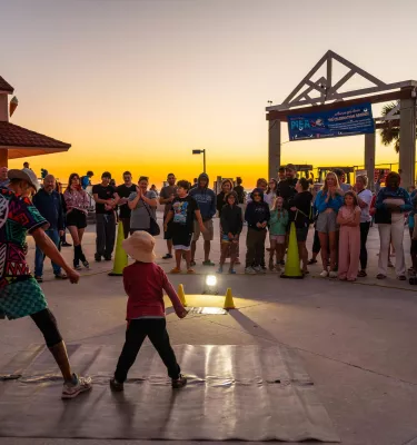 a performer engages with a small child at the sunsets at Pier 60 nightly celebration