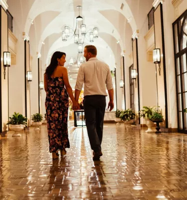 a woman and a man walk down a shiny tiled hallway with arched ceilings at the Vinoy Resort & Golf Club