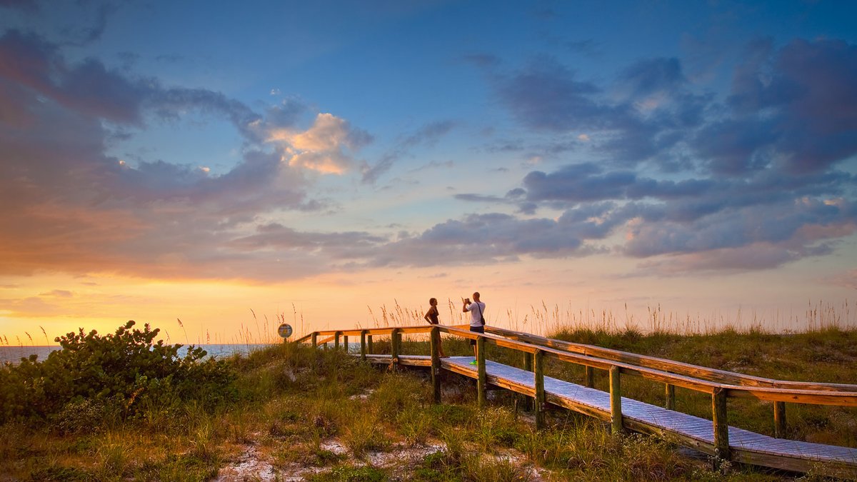 Ein Paar fotografiert bei Sonnenuntergang an einem Strandweg am wunderschönen Pass-a-Grille Beach in der Nähe von St. Pete Beach, Florida