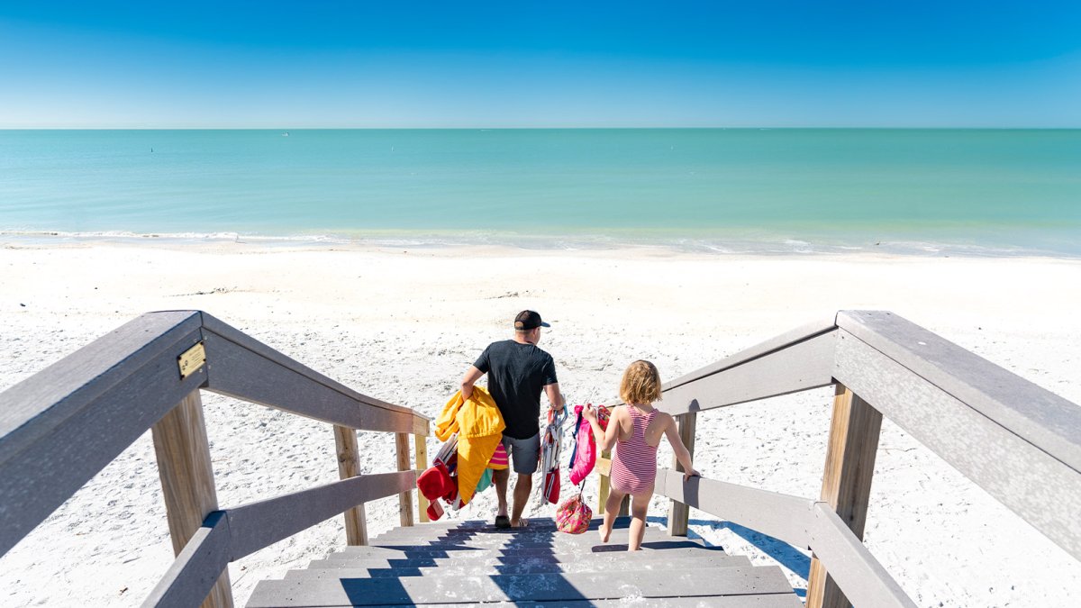 A family arriving at Sunset Beach over a wooden walkway.