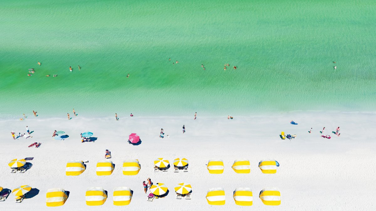 Aerial view of yellow cabanas, white sand and emerald-green water of Clearwater Beach.