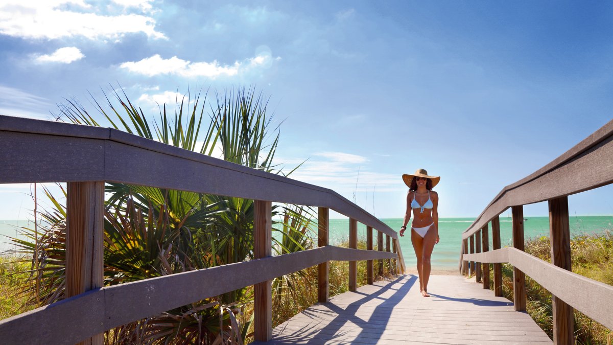 A young lady dressed in bikini walking Indian Rocks Beach boardwalk.