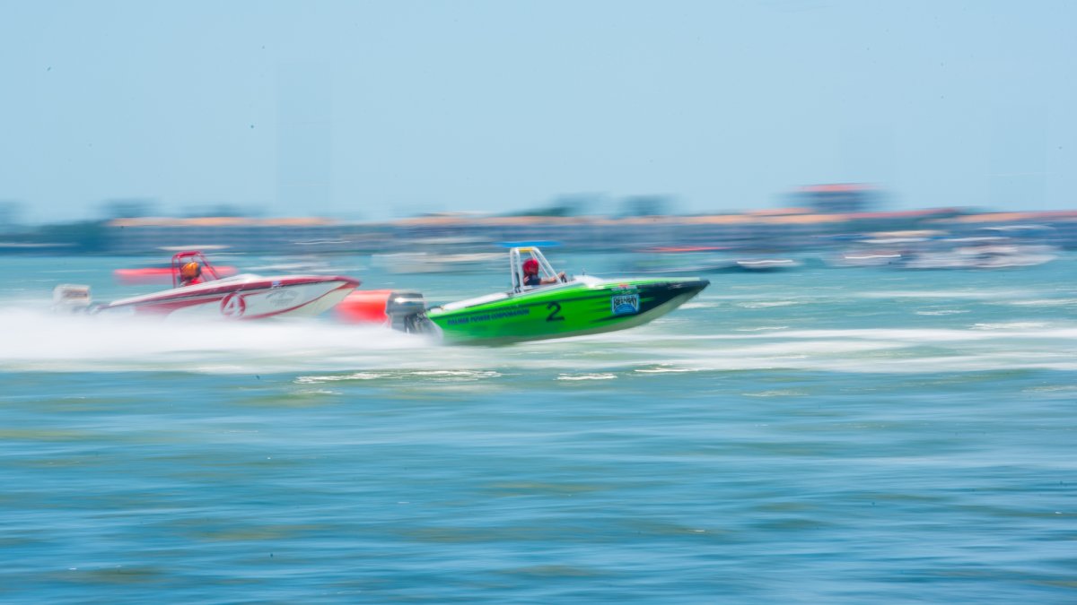 Two speed boats going very fast. The water and the surroundings are blurry.