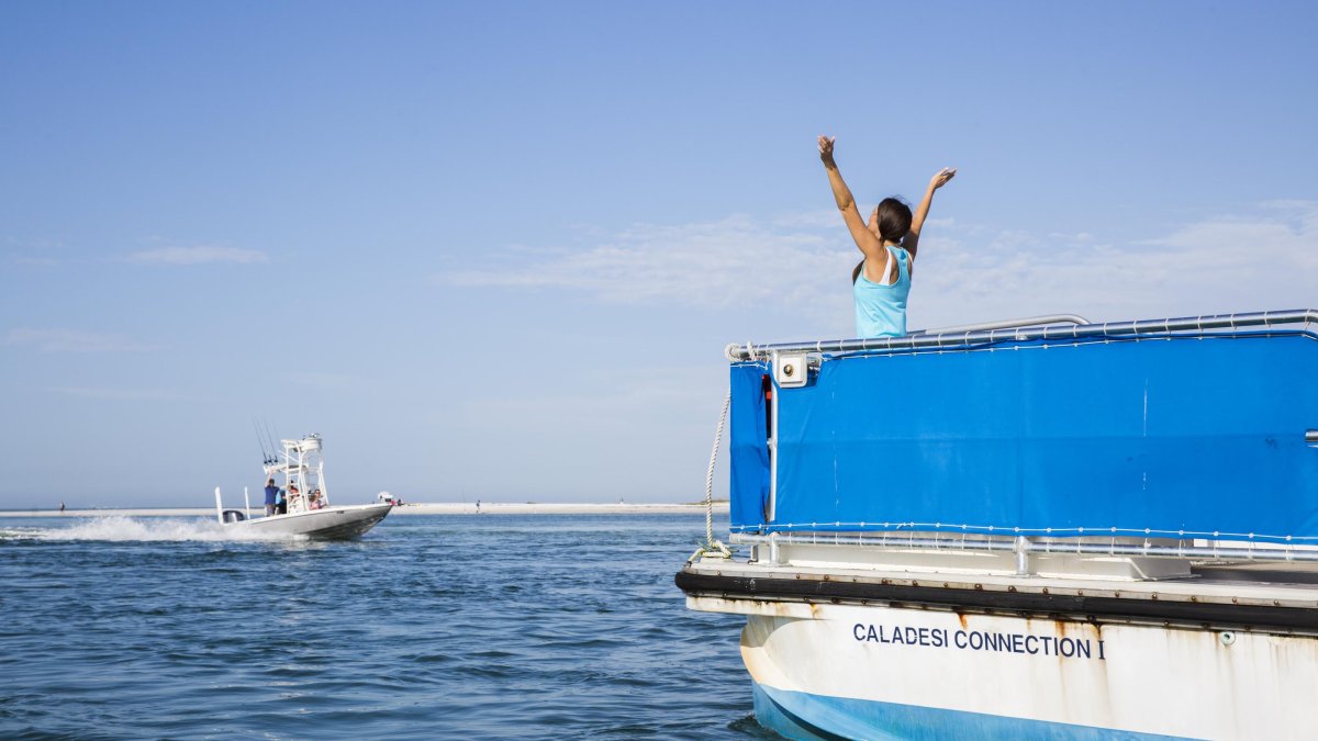 A woman stretches her arms out wide on the Caladesi Island State Park Ferry