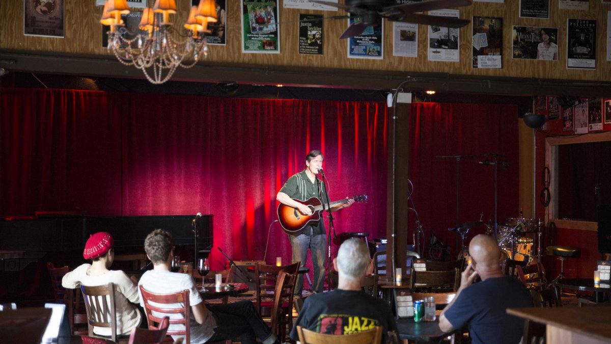 A man plays a guitar in front of a small crowd at Hideaway Cafe on Central Ave in downtown St. PEte