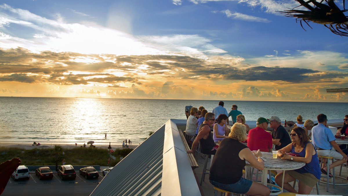 People dining on the rooftop of a rooftop bar at sunset