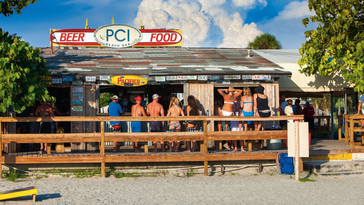 Exterior shot of people drinking at Postcard Inn Beach Bar & Snack Shack in St. Pete Beach