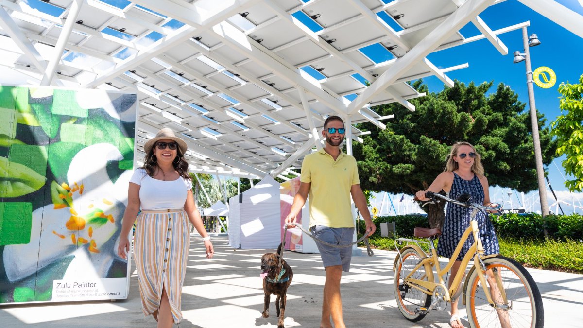 Three people and a dog stroll down the St. Pete Pier Marketplace