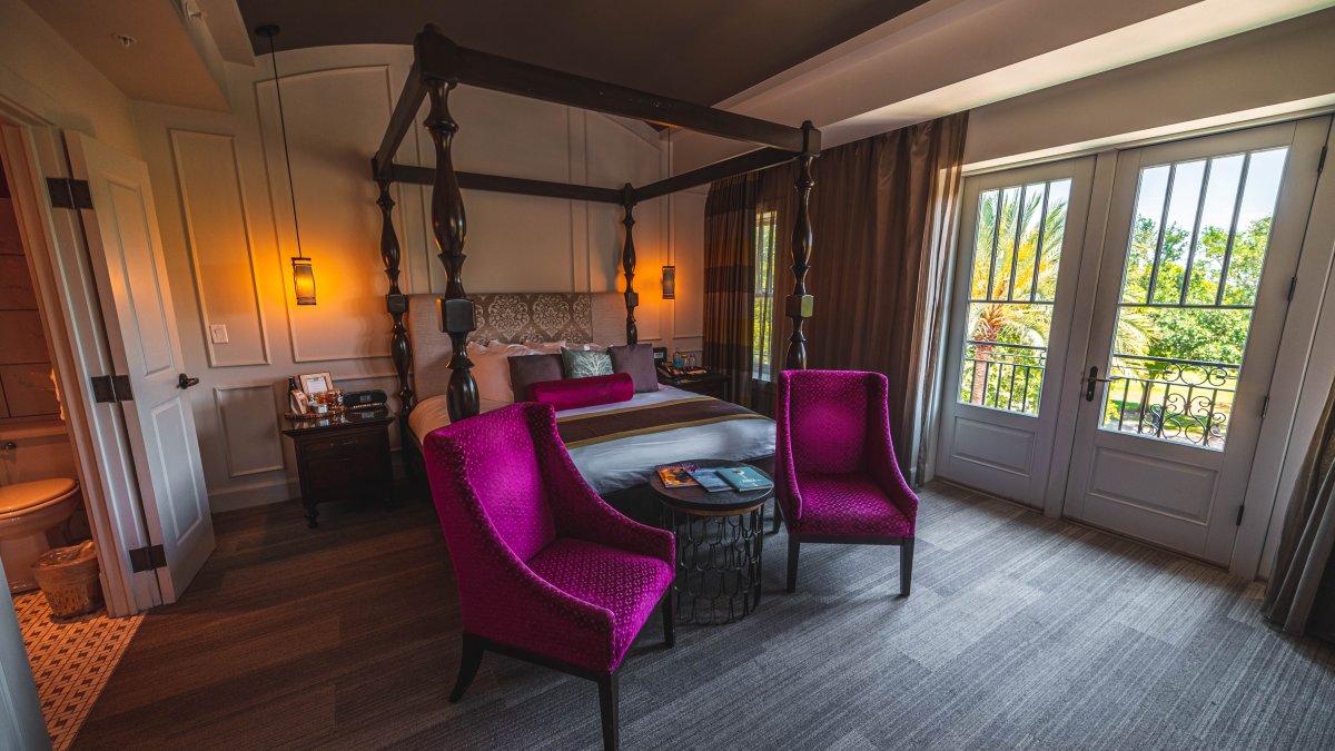 Magenta chairs and antique looking bedroom with french doors at The Birchwood boutique hotel