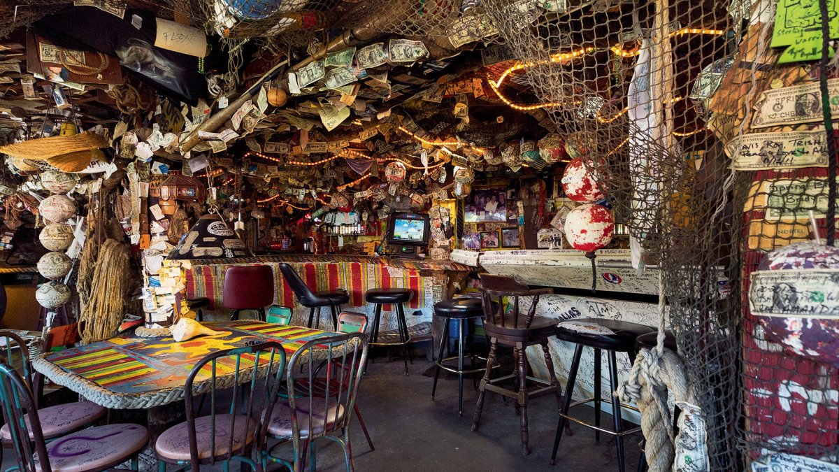 dentro de un bar de buceo con decoración de pesca, redes y dólares grapados a la pared y al techo.