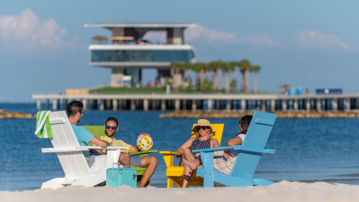 Four friends lounge in Adirondack chairs at spa beach at the new St. Pete Pier 