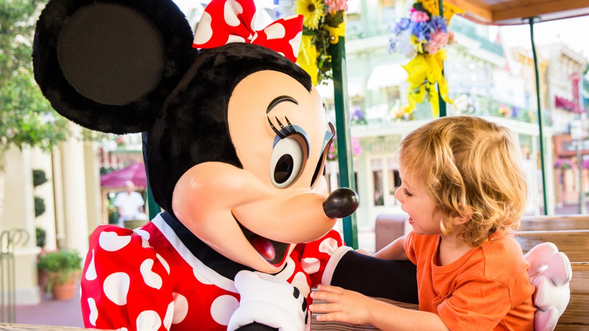 A person in a Minnie Mouse costume plays with a child at Disney World