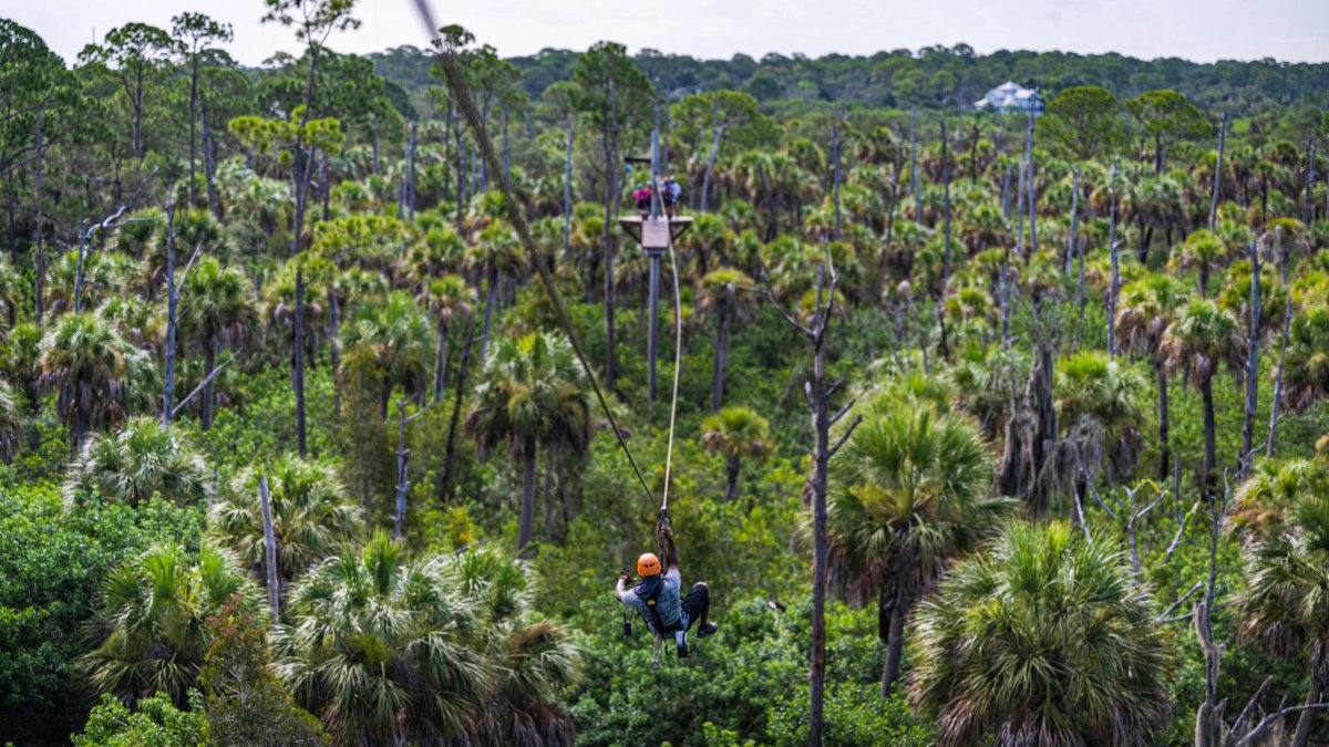 A person rides the zipline at Empower Adventures