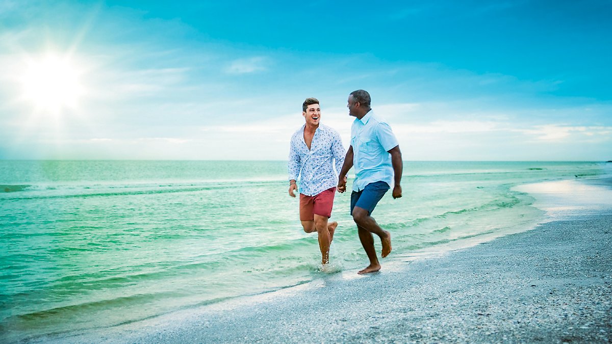 Two gay men walk hand-in-hand at the surf's edge on Clearwater Beach