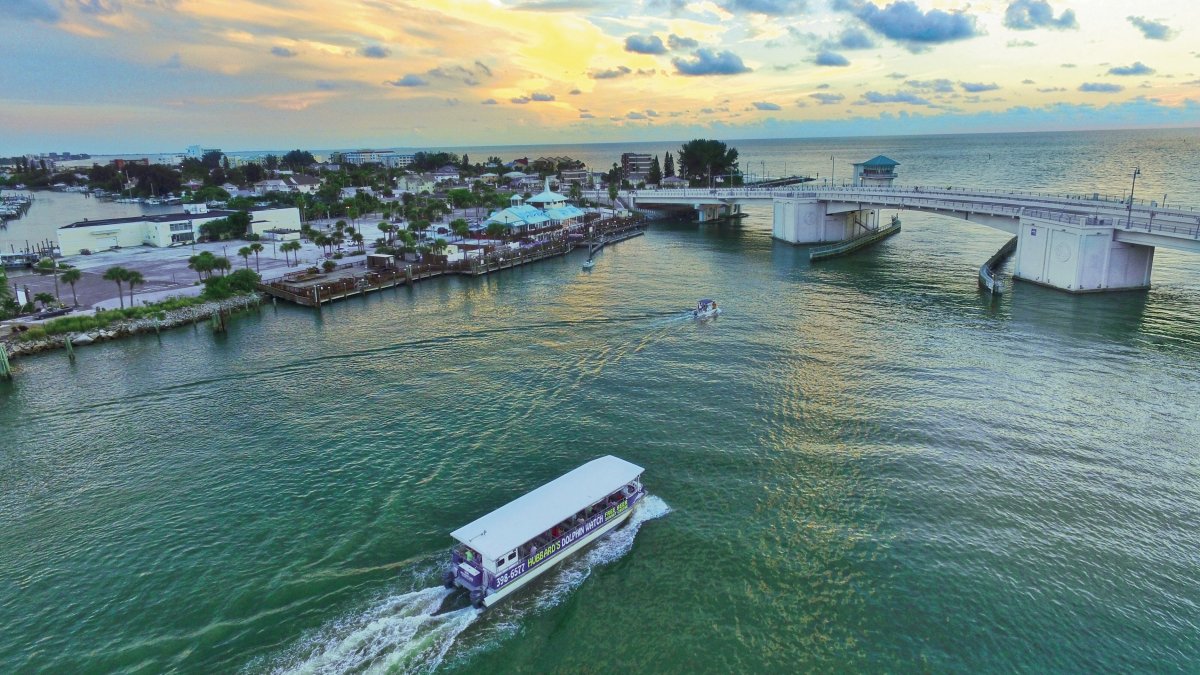 An overview of John's Pass during sunrise. A deep fishing boat is passing going by.